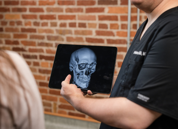 Oral surgeon pointing at TMJ in a patient scan.